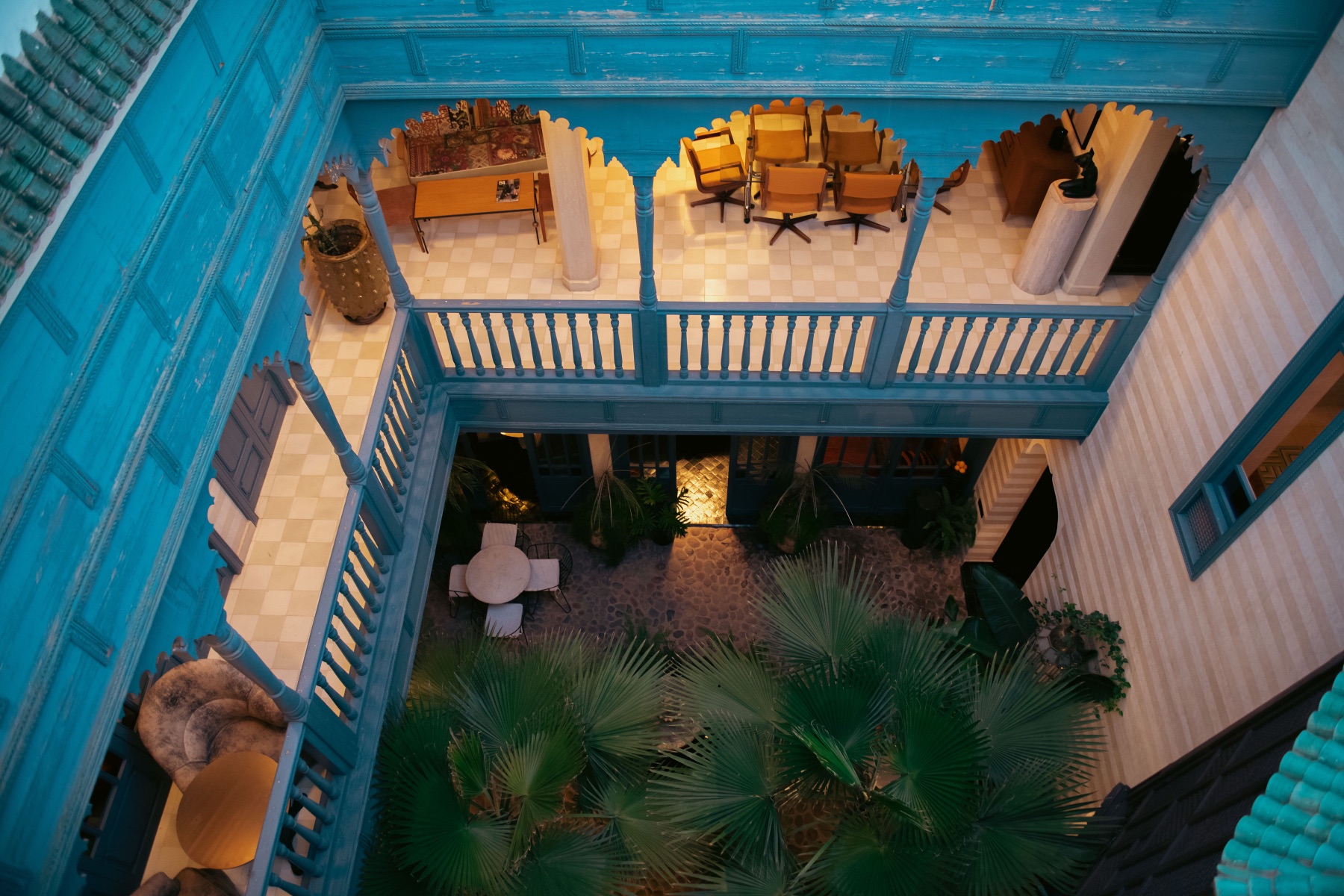 Looking down into the turquoise gallery, mustard lounge chairs above the planted courtyard