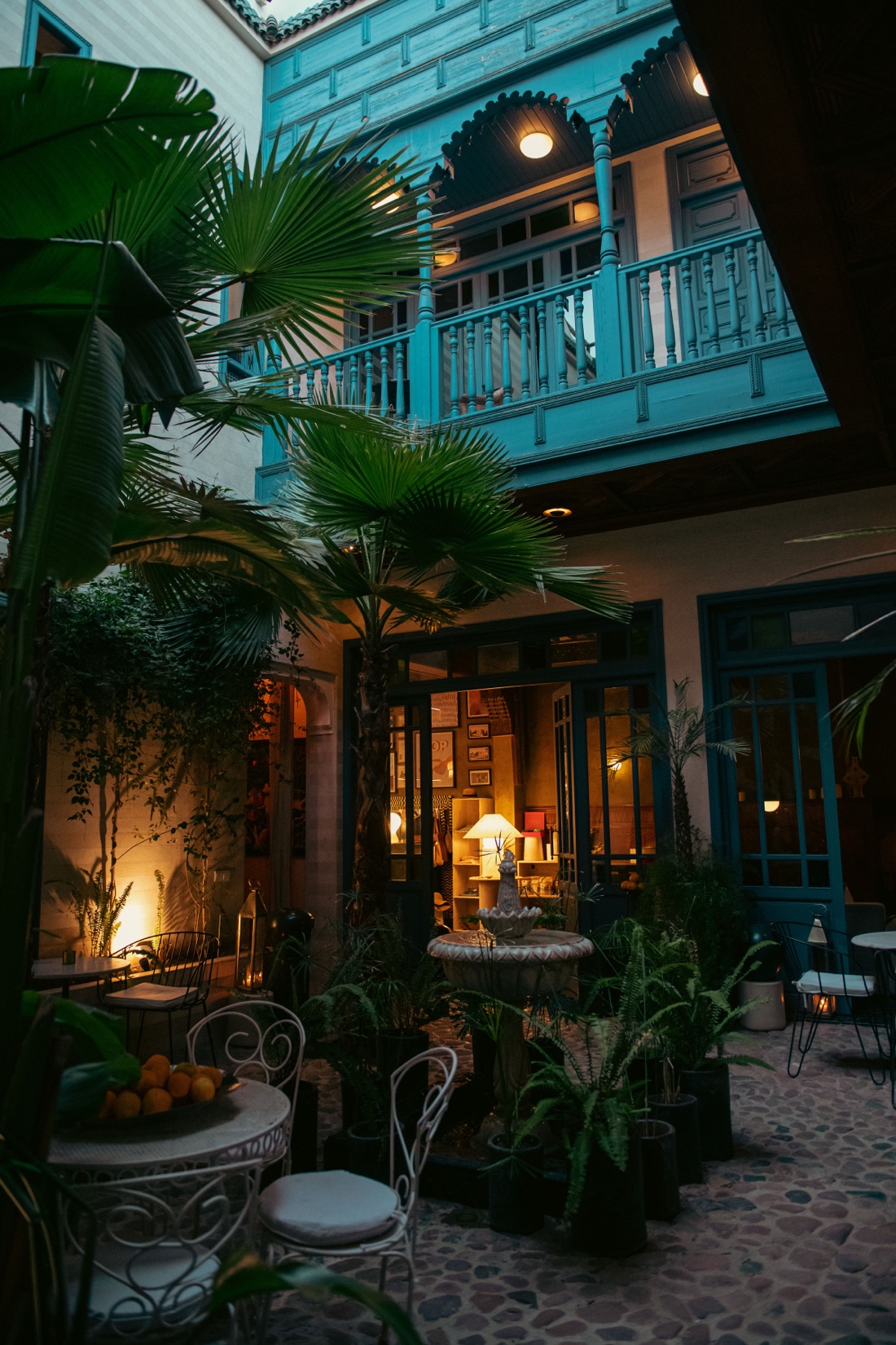 The fountain courtyard at dusk, palms rising past the turquoise carved balcony