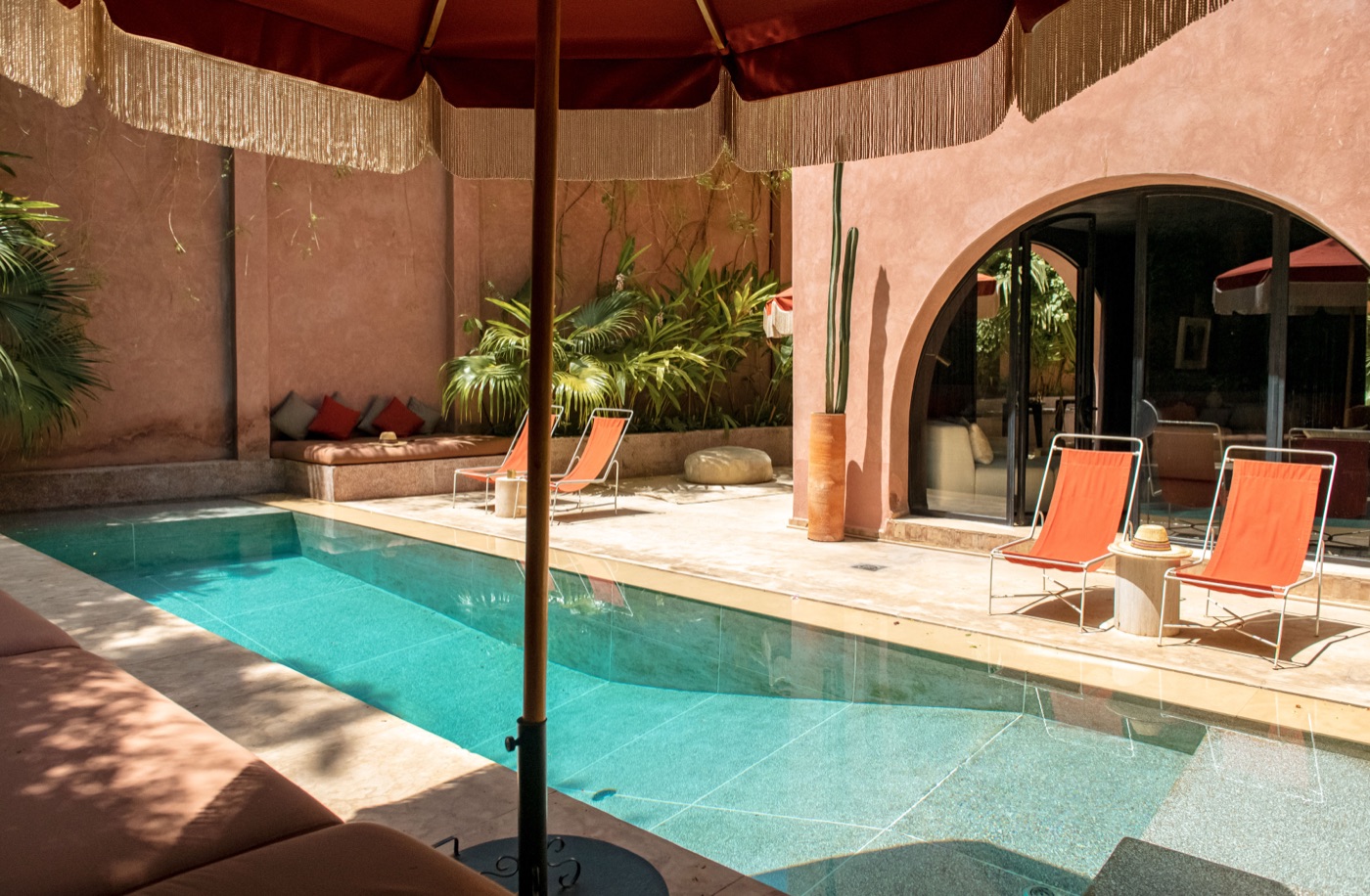 Heated plunge pool under a fringed parasol, orange loungers beside an arched terrace door