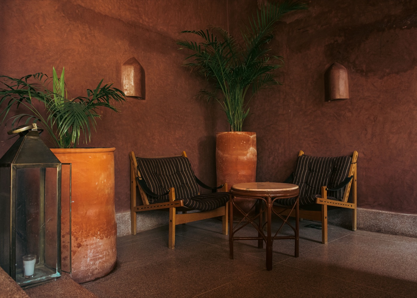 Terracotta lounge corner with lanterns, potted palms and safari chairs